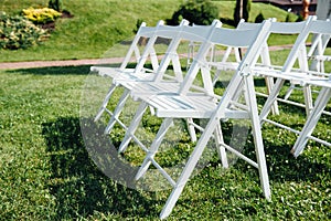 Rows of white folding chairs on lawn