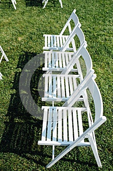 Rows of white folding chairs on lawn
