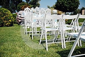 Rows of white folding chairs on lawn