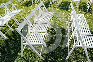 Rows of white folding chairs on lawn