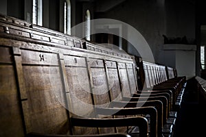 Rows of wooden pews in a closed down building