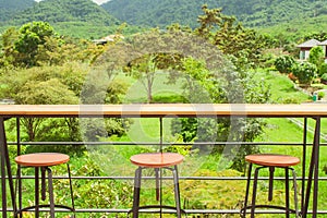 Rows of wooden stools and counter bar on outdoor terrace with beautiful landscape viewpoint.