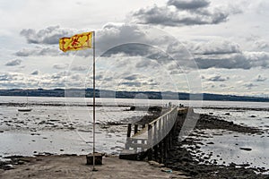 The Royal Banner of Scotland flag flying at a pier in the Firth of Forth in Culross, Scotland, UK.