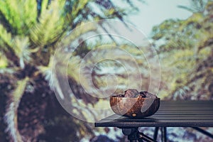 Royal dates fruit in a bowl of coconut on a table in a palm tree grove.