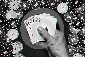 Royal flush in the game of poker in the hands of the player on the background of a green table with gaming chips