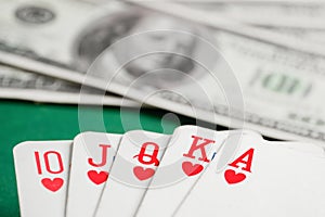 Royal flush of hearts cards during poker with dollars on green table