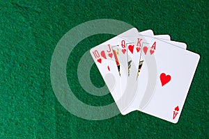 Royal flush of hearts on green background