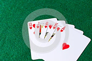 Royal flush of hearts on green background