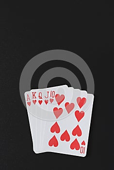 Royal flush poker hands on a black background, playing cards, copyspace for you marketing text