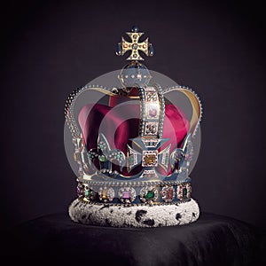 Royal golden crown with jewels on pillow on black background. Symbols of UK United Kingdom monarchy