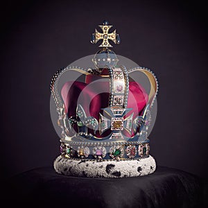 Royal golden crown with jewels on pillow on black background. Symbols of UK United Kingdom monarchy photo