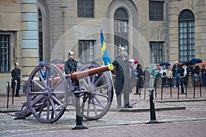 The Royal Guardsman with a banner at an old artillery gun. Ceremony of guard divorce near the royal palace. Stockholm