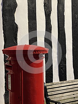 Royal mail post box against black and white striped wall