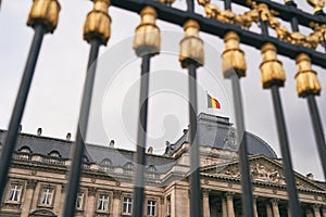 The Royal Palace in Brussels, Belgium. View through the metal fence with golden details. National flag of the Kingdom of