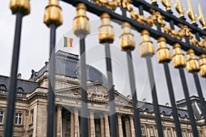 The Royal Palace in Brussels, Belgium. View through the metal fence with golden details. National flag of the Kingdom of