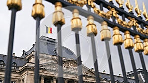 The Royal Palace in Brussels, Belgium. View through the metal fence with golden details. National flag of the Kingdom of