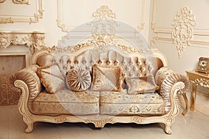 Royal sofa with pillows in beige luxurious interior with ornament frame wall