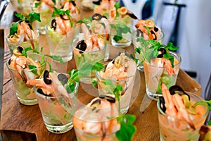Royal tiger prawn snacks. Shrimps, greens, olives dressing appetizer in glasses shots. Fresh seafood catering service