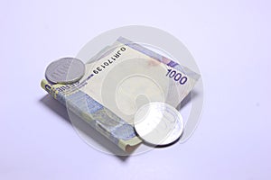 Rp.1000 banknotes and coins with a white background