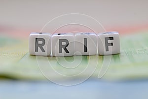 RRIF letters on white blocks with bills on a clear background