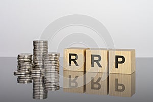 RRP - text on wooden cubes on a cold grey light background with stacks coins photo