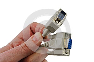 RS-232 communication cables, male and female, held in left hand of adult person, white background