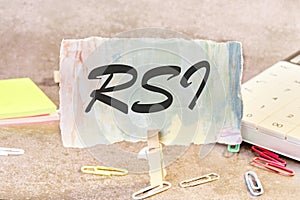 RSI Relative Strength Index text on a piece of paper on the table with a clothespin clamped