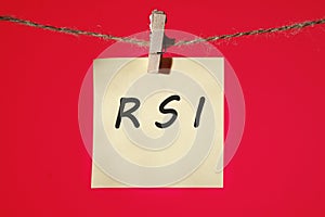 RSI Relative Strength Index text on a yellow sticker hanging on a rope with clothespins on a red background