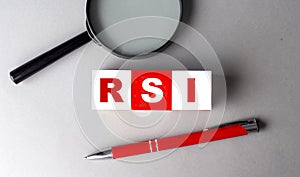 RSI - Relative Strength Index word on wooden cubes with pen and magnifier