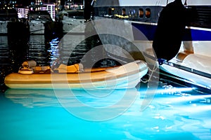 A rubber boat is moored to a yacht in the seaport. Night Scene