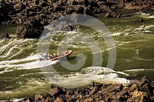 Rubber boat sailing on green waters in IguazÃº national park, Misiones, Argentina with stone shores at both sides.