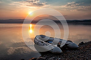 Rubber boat on the shore of the picturesque coast against the backdrop of sunset