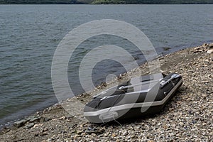 A rubber boat stands on the bank of the river.A means of transportation on the water