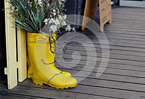 Rubber boots decorated with branches and white flowers in the tops on the wooden flooring on the street in spring macro