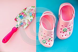Rubber boots and garden tools on bright background.kids summer sandals and shovel with flowers pattern.Kid`s toys and