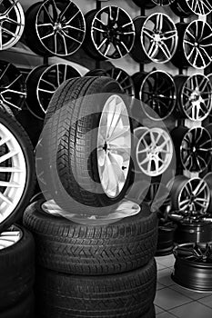 rubber car wheels lie in a pyramid against the background of car alloy wheels in a store. Sale and replacement of wheels