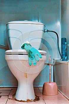 Rubber glove on the lid of an old dirty toilet bowl