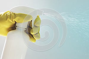 Rubber gloved hand holding a white spray bottle