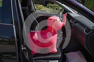 Rubber inflatable pink elephant animal toys on the front seat of a car, background with shadow reflection