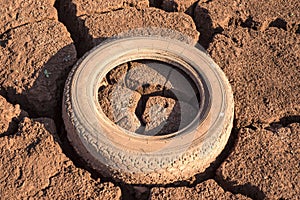 Rubber pollution. Old car tires, wheels, in the old dry cracked earth, close up