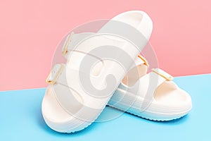 Rubber summer flip-flops on pink and blue background close-up.