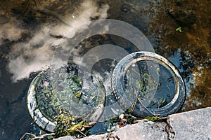 Rubber tire wheels near shore of water reservoir, pollution of environment and sea