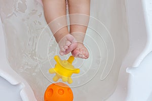 Rubber toys in the bathtub with baby feet
