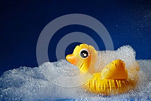 Rubber yellow duck toy on a blue background in foam. Personal hygiene