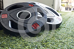 Rubberized barbell plates on the artificial grass mat of a home gym