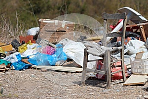 Rubbish dumped at side of road with chair.