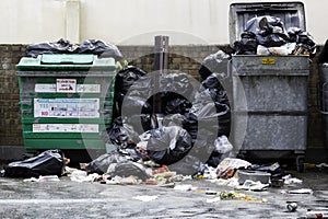 Rubbish or garbage bins overflowing with rubbish and rubbish bags with garbage or rubbish all over the street photo