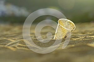 Rubbish Plastic cup on the golden beach sand of the ocean, playa de las Teresitas, Tenerife. Environment conservation