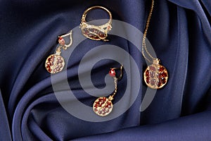 Rubies ring, necklace and earrings on blue silk background with