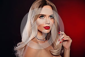 Ruby pendant jewelry. Beauty portrait of blonde woman with red lips, long healthy shiny blond hair style and manicured nails.